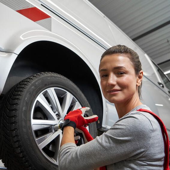 Volkswagnov tehnik menja platišča na vozilu. Avto je dvignjen na dvigalu v mehanični delavnici.