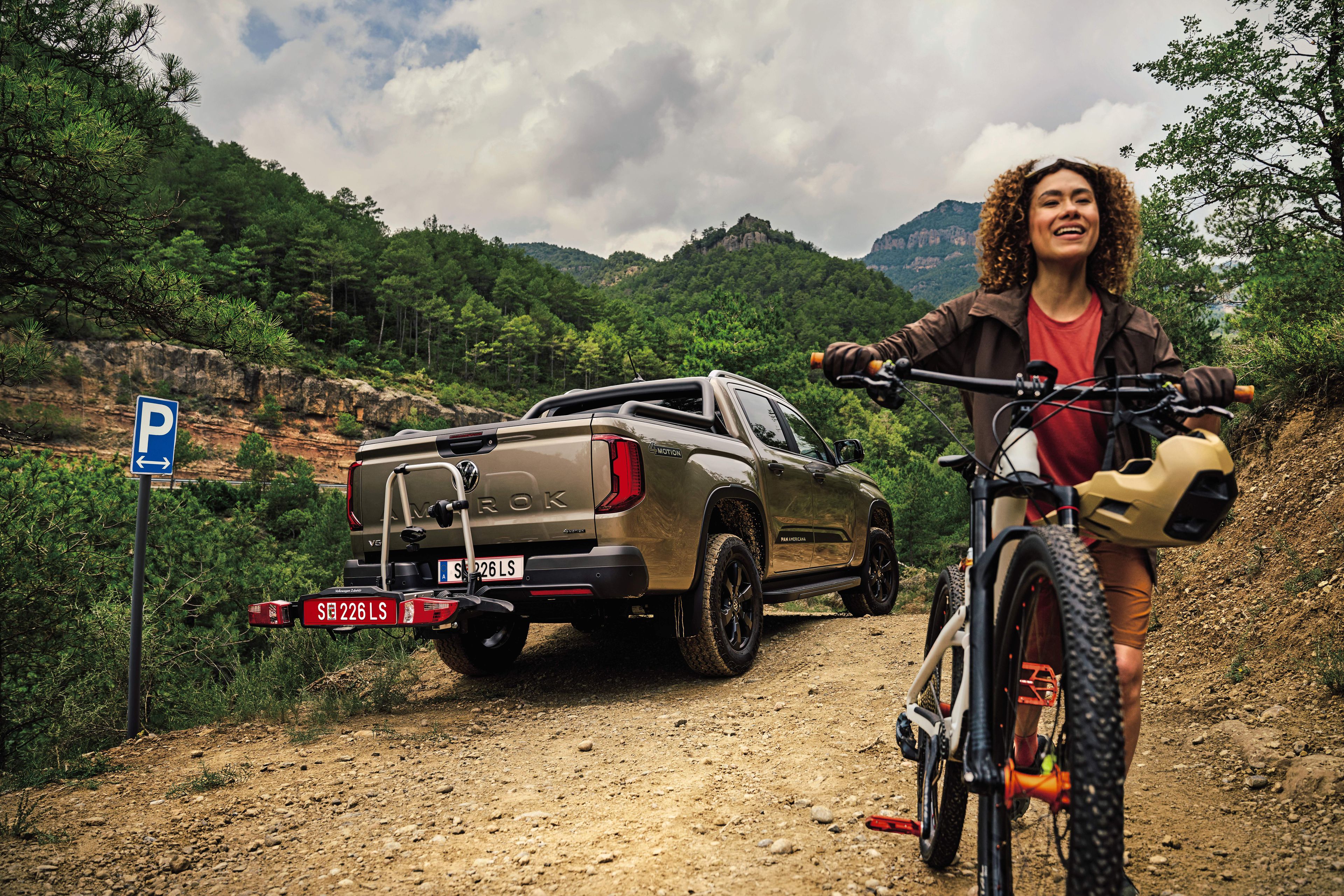 Amarok parkiran v gozdu, ženska z gorskim kolesom se odpelje stran