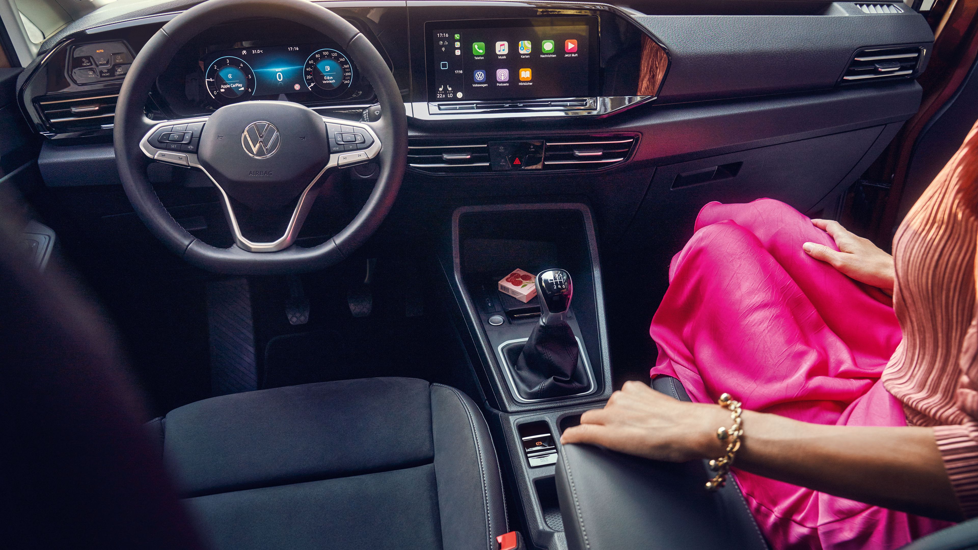 Eine Frau sitzt in einem VW Caddy. Zu sehen ist der Innenraum und die Digitalanzeigen.