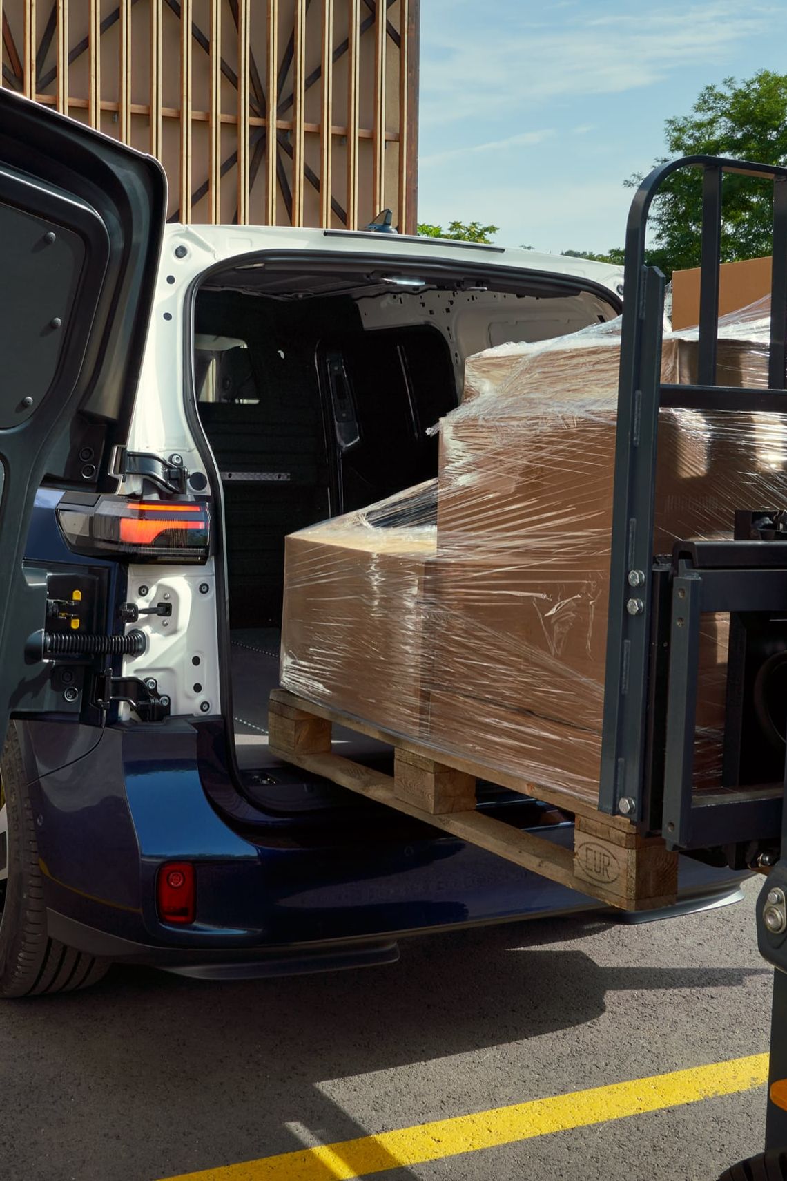 Ein weiß blauer ID. Buzz Cargo mit Heckflügeltüren wird mit einem Gabelstapler beladen