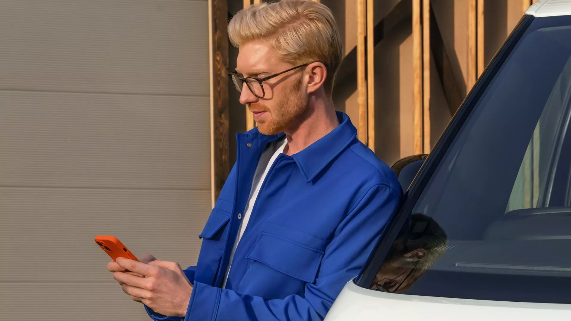 Mann lehnt an ID. Buzz Cargo und verwendet sein Smartphone