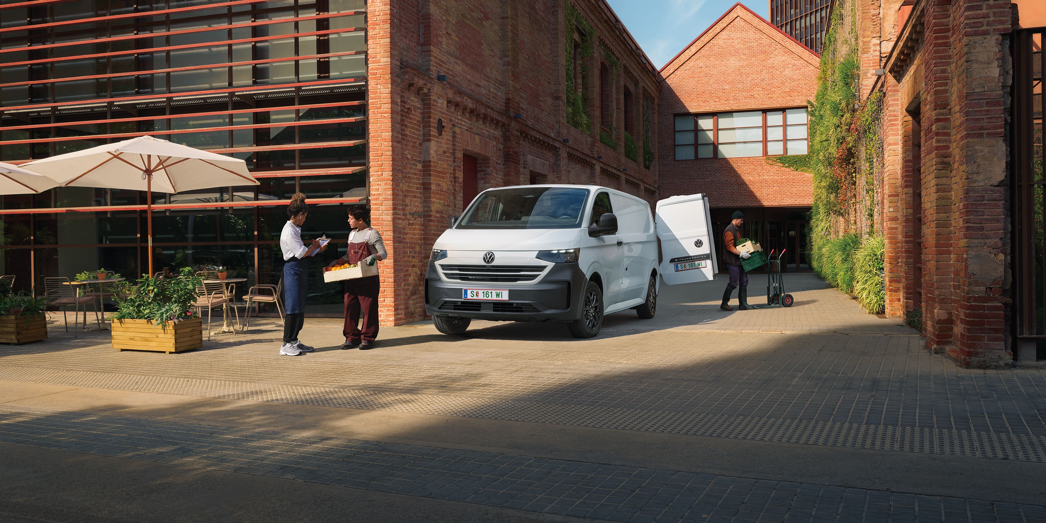 VW Transporter furgon v beli barvi stoji pred hišo