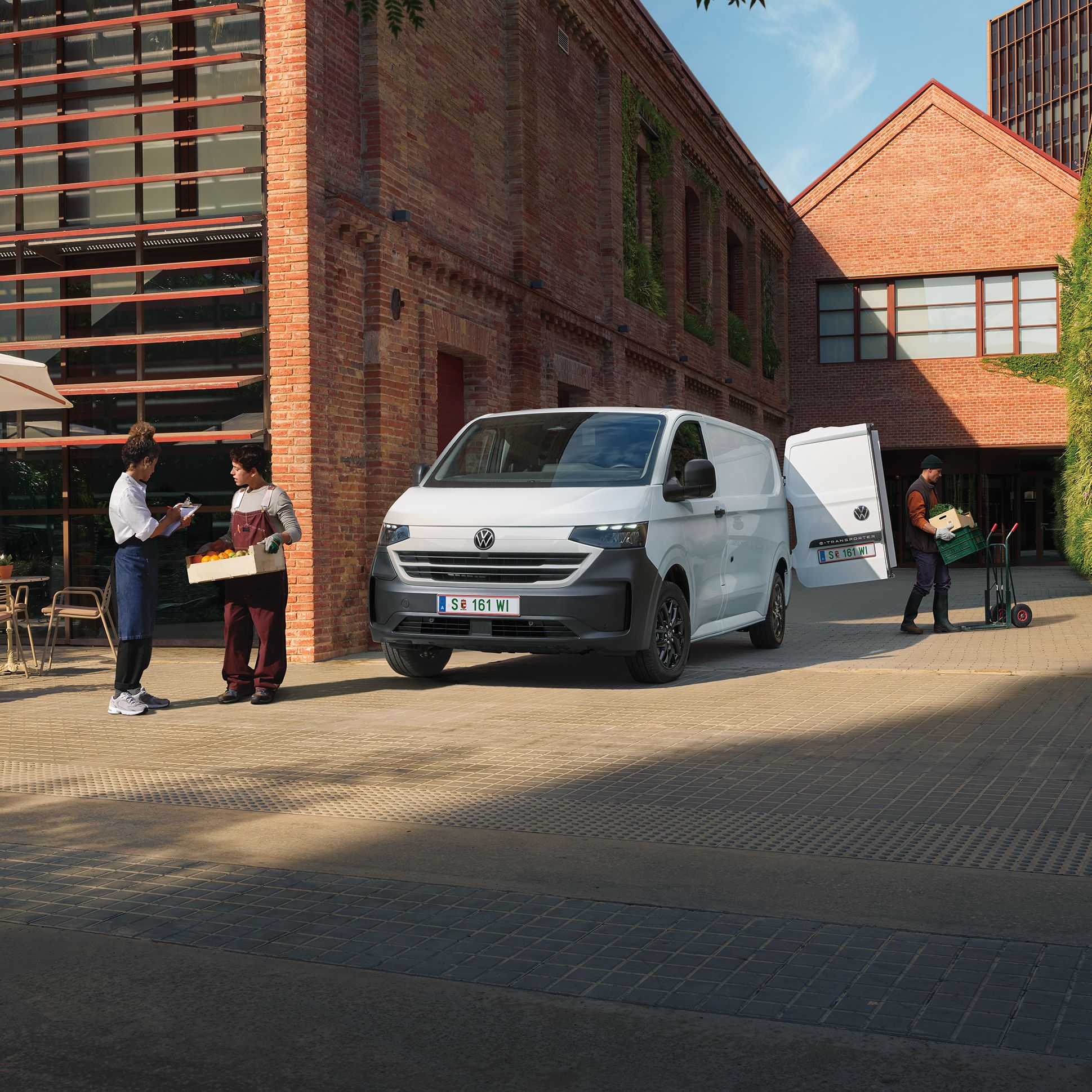 VW Transporter furgon v beli barvi stoji pred hišo