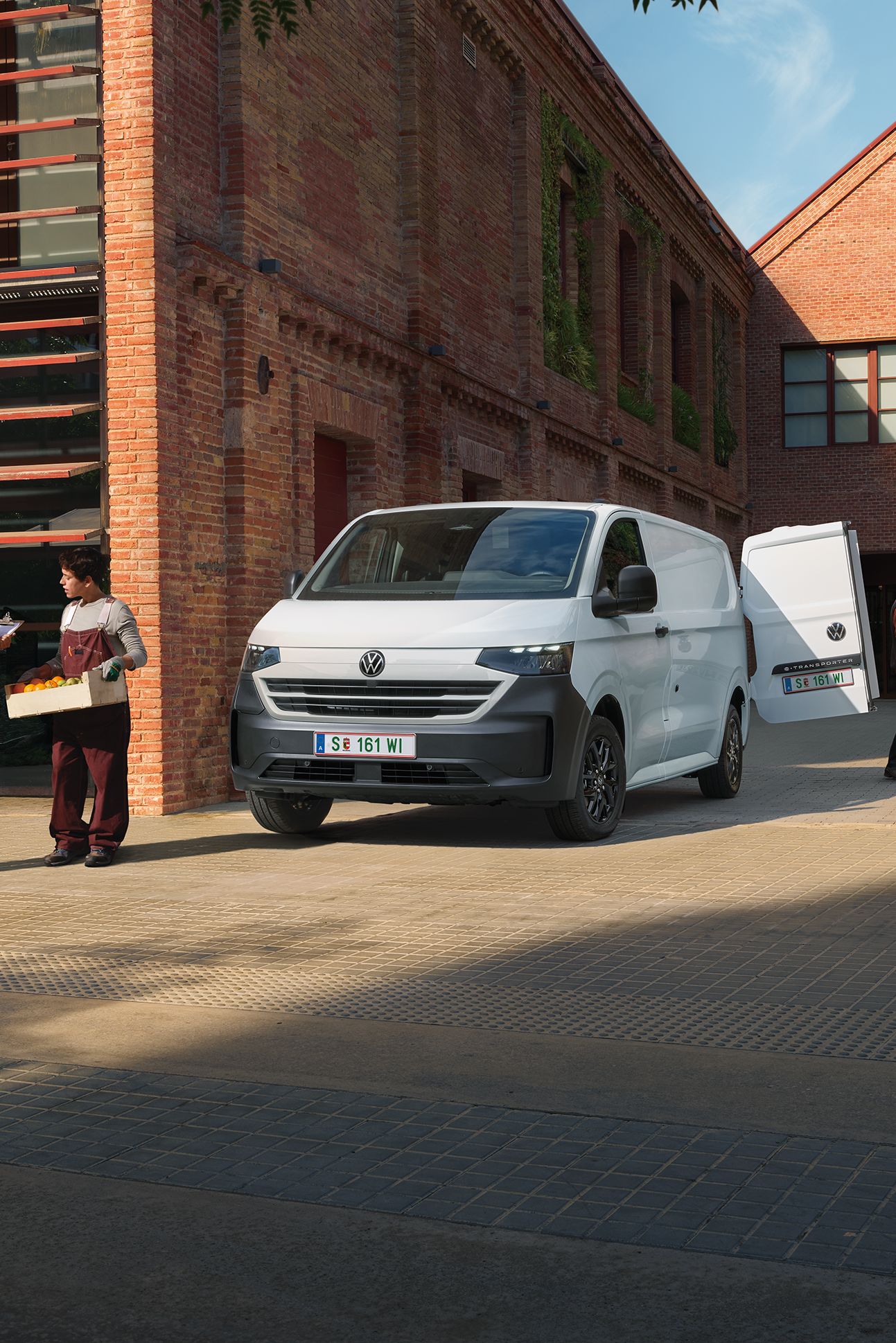 VW Transporter furgon v beli barvi stoji pred hišo