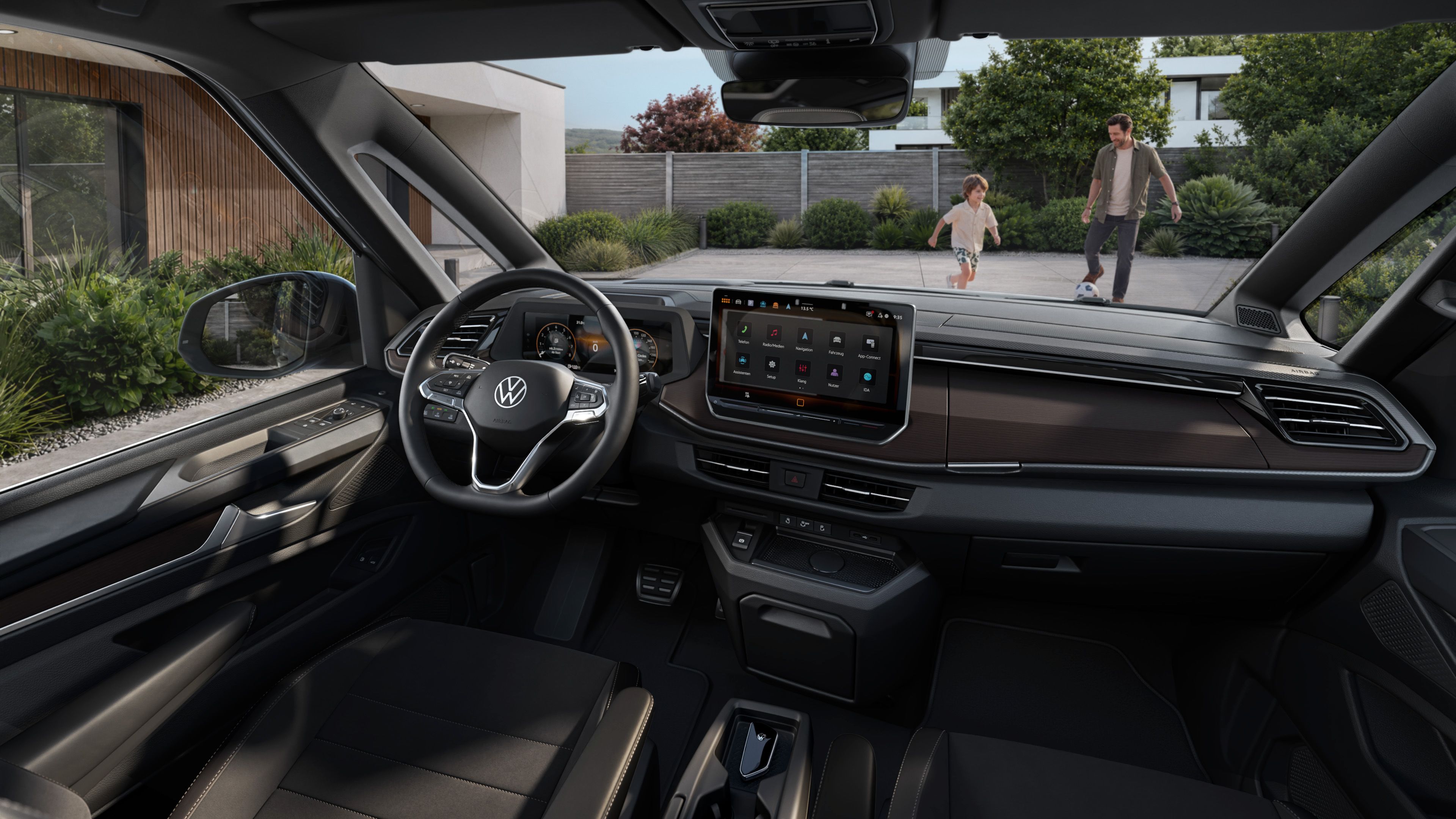 Notranjost sodobnega Volkswagnovega osebnega vozila, fotografirana z voznikove perspektive, z velikim osrednjim zaslonom na dotik in digitalnim merilnikom. Preko vetrobranskega stekla sta zunaj vidna otrok v gibanju in odrasla oseba, ki hodita po dovozu pred hišo s sodobno arhitekturo. Avto je parkiran, okolico pa obdajajo zelenje in urejen vrt.