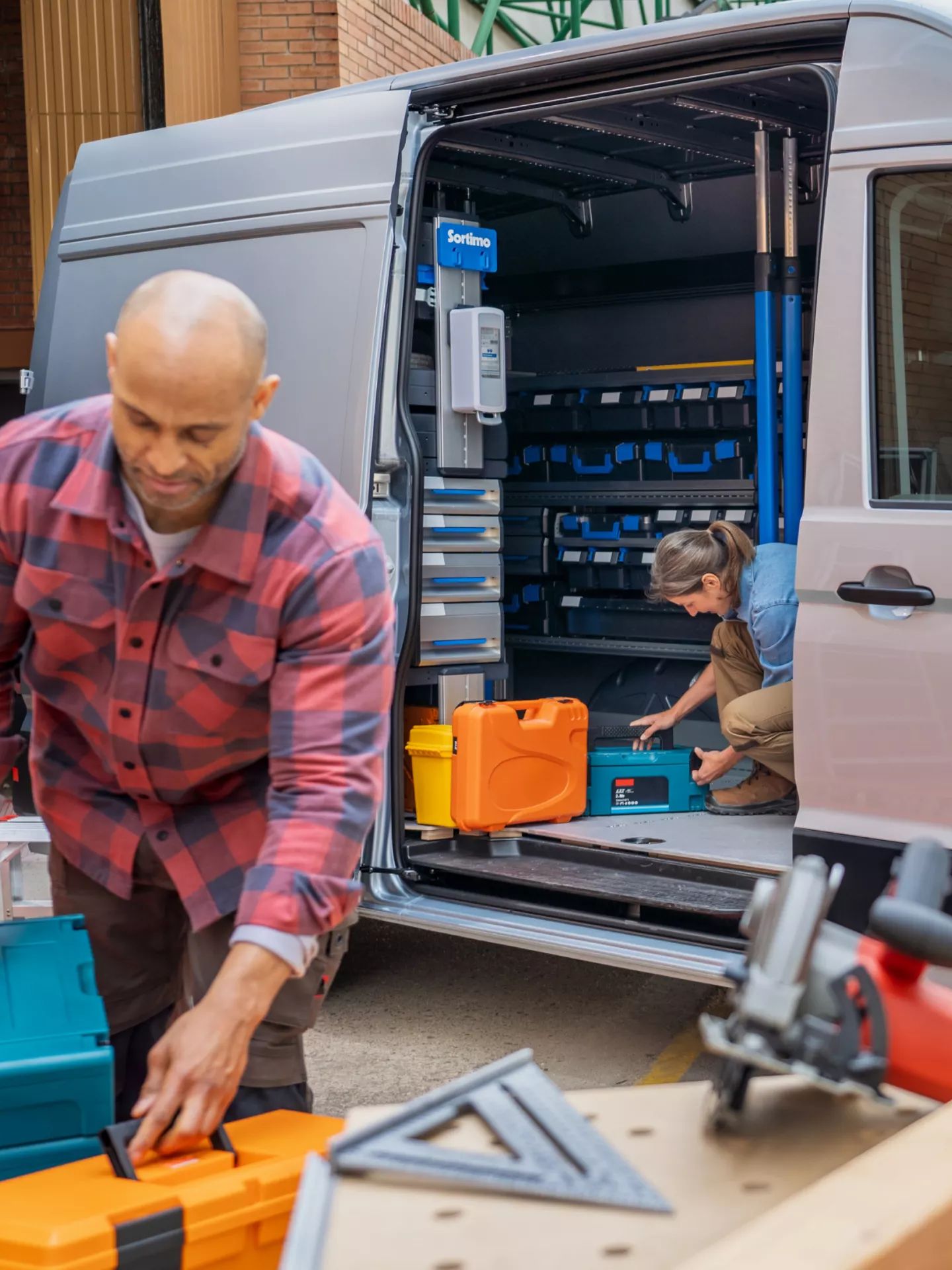 Zwei Handwerker nutzen einen VW Crafter als Arbeitsfahrzeug, geöffnete Schiebetür
