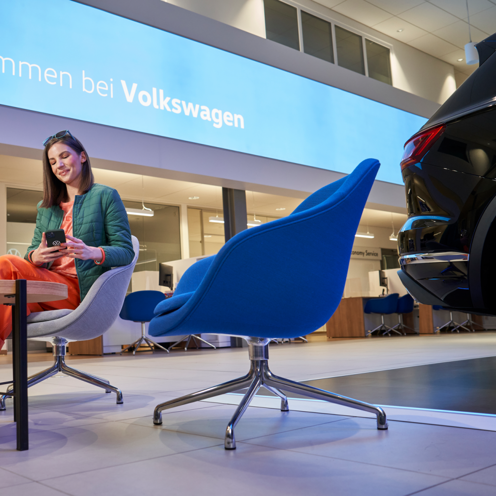 Frau sitzt auf einem Sessel und verbindet sich mit der WeConnect App auf ihrem Smartphone