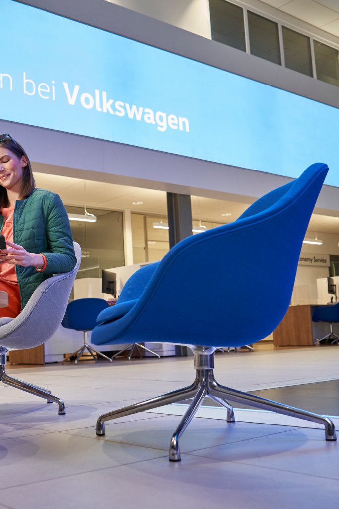 Frau sitzt auf einem Sessel und verbindet sich mit der WeConnect App auf ihrem Smartphone