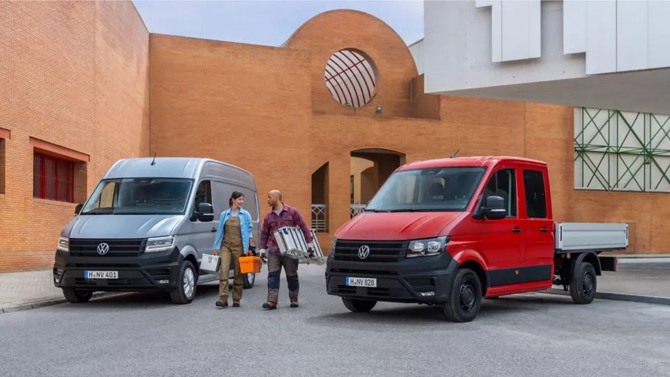 Ein Crafter Kastenwagen und ein Pritschenwagen stehen nebeneinander,  zwei Handwerker gehen daneben