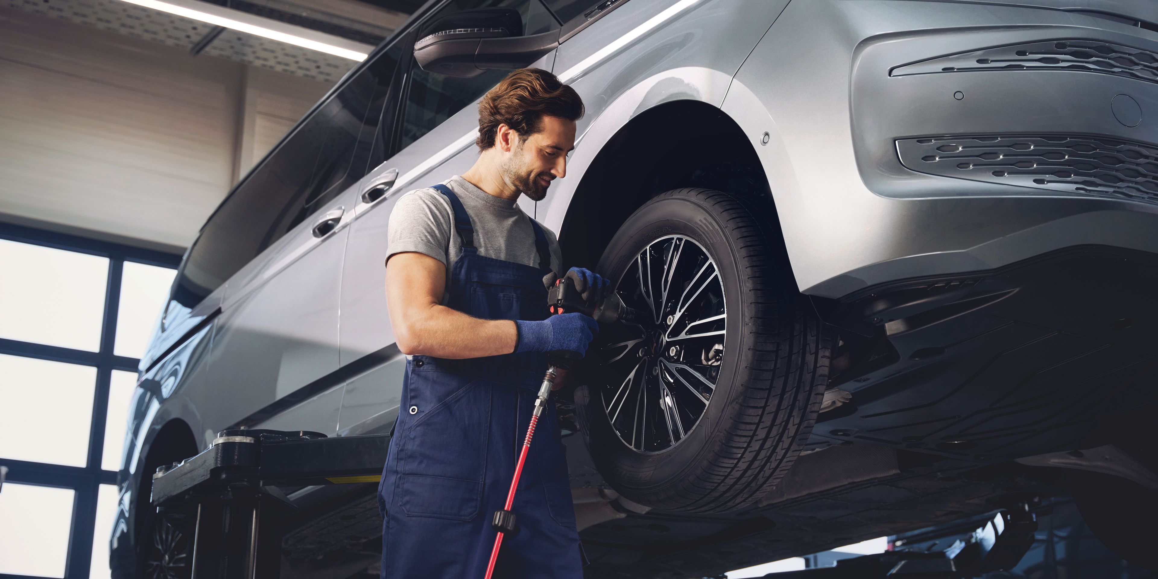 Servisni tehnik menja kolesa na VW Multivanu.