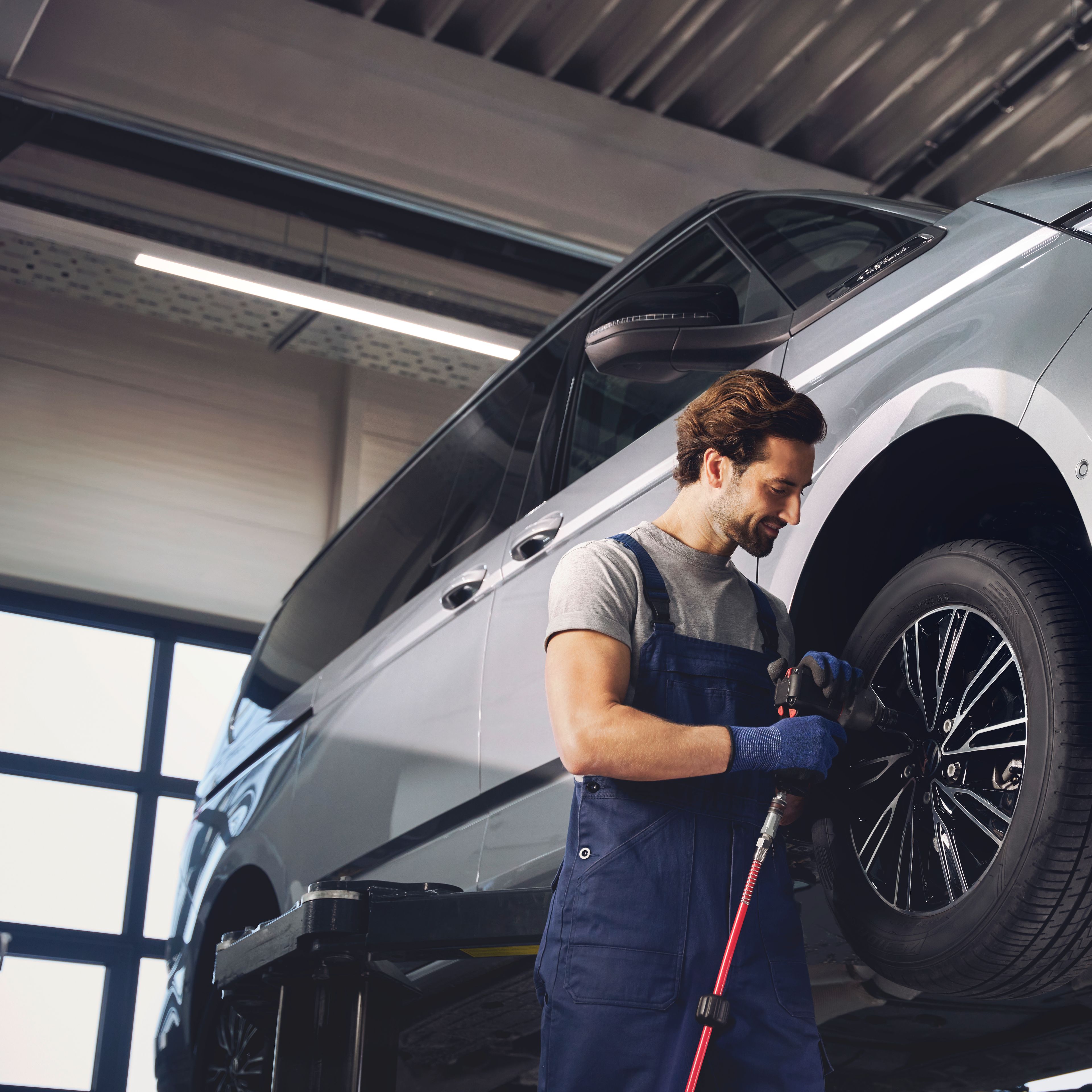 Servisni tehnik menja kolesa na VW Multivanu.