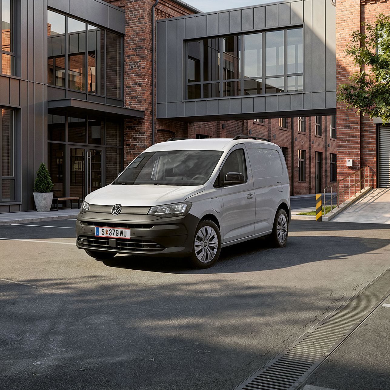 Der neue Caddy Cargo in Weiß steht vor Gebäude.