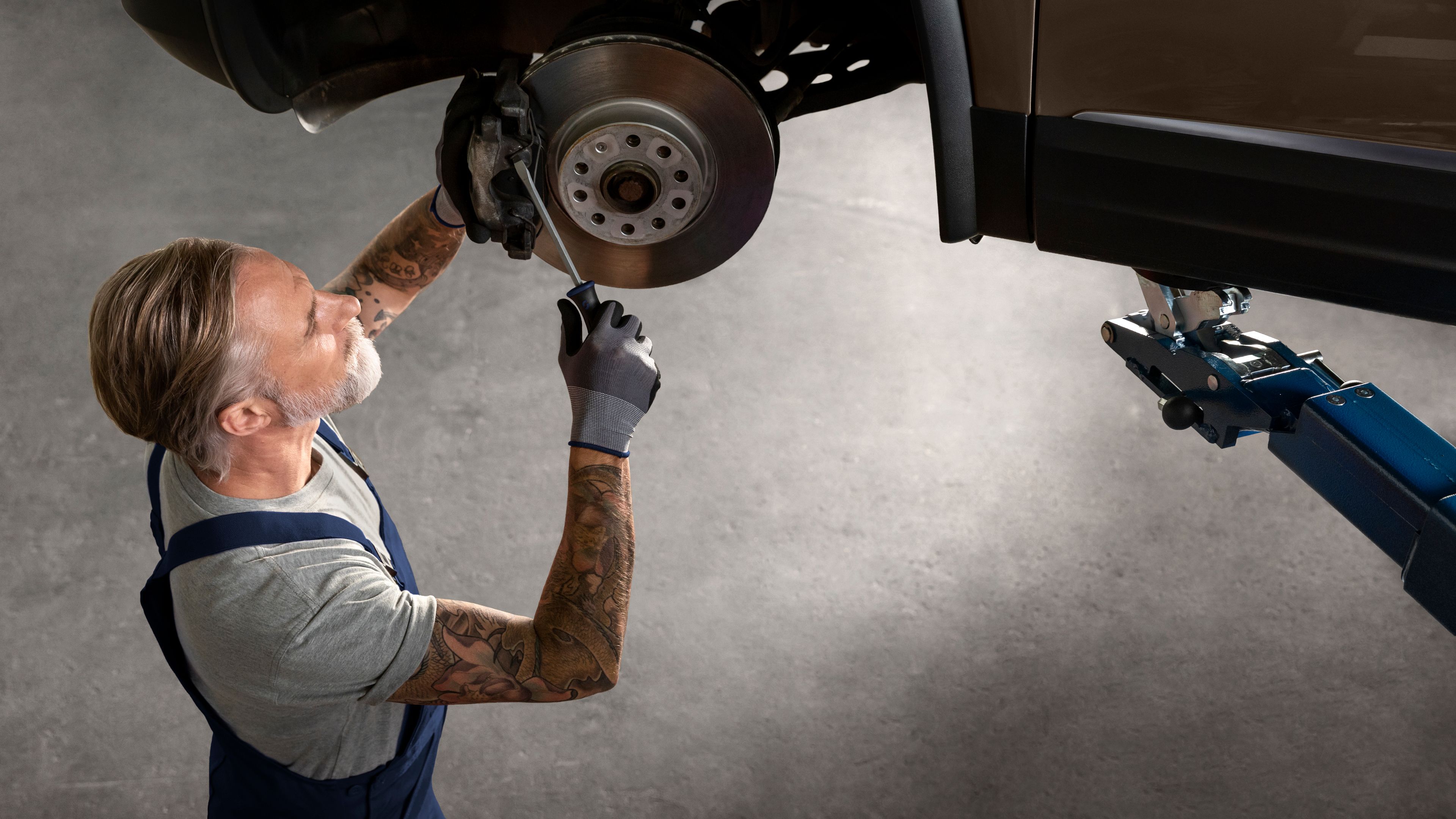 Ein VW Mechaniker bei der Arbeite an den Bremsen und Bremsscheiben